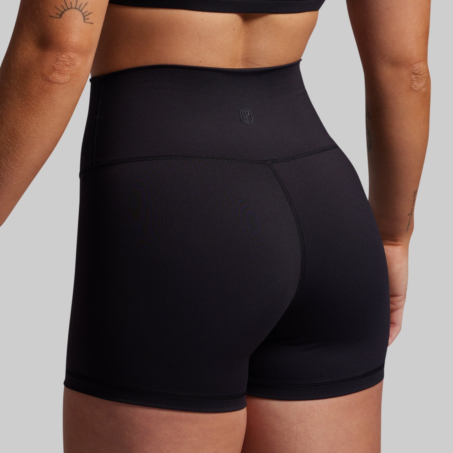 Black athletic shorts worn by a person on a plain background