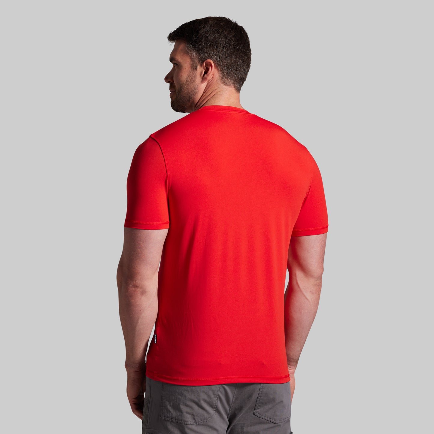 Man wearing a red t-shirt against a gray background