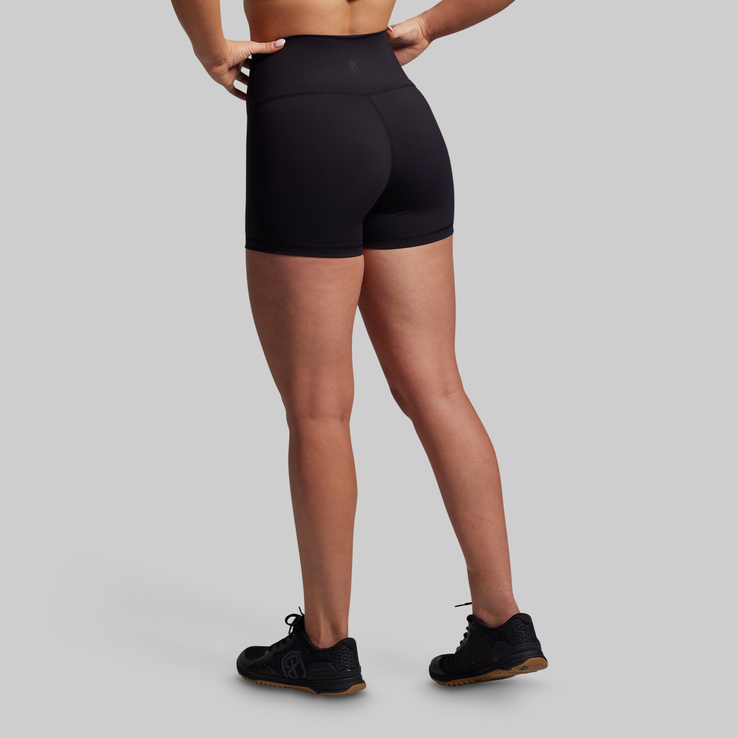 Person wearing black athletic shorts on a gray background