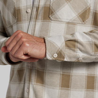 Close-up of man adjusting the cuff of a white and tan plaid flannel