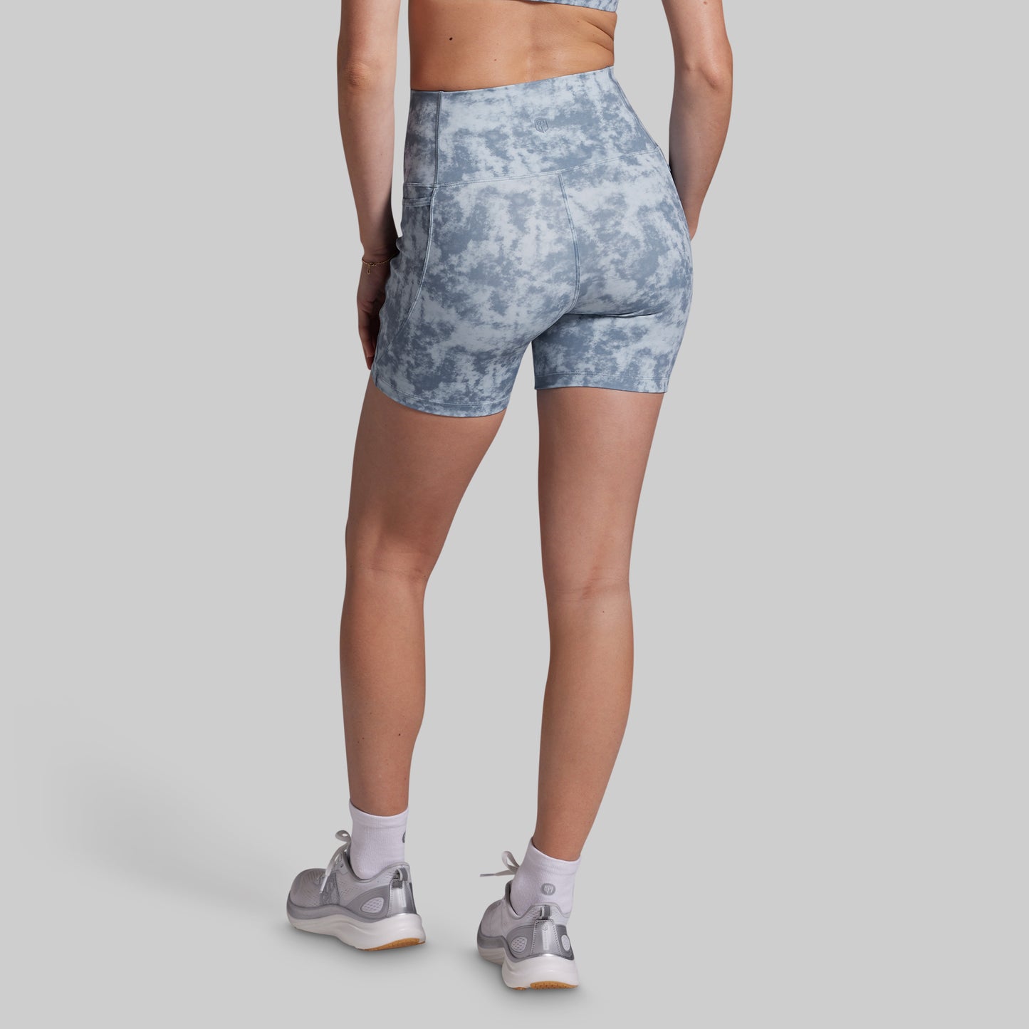 Person wearing blue tie-dye shorts on a gray background