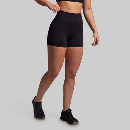 Person wearing black athletic shorts on a gray background