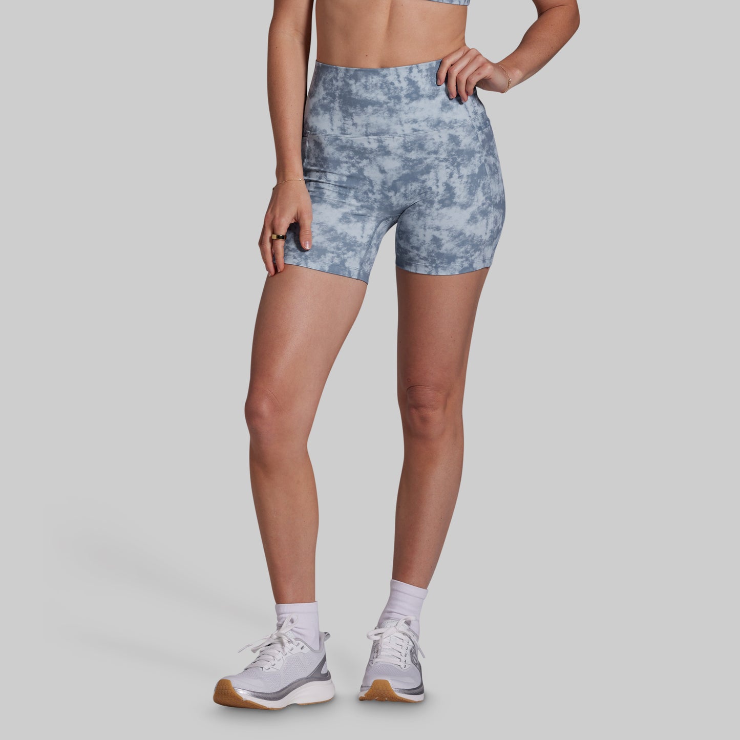 Person wearing blue tie-dye shorts on a gray background