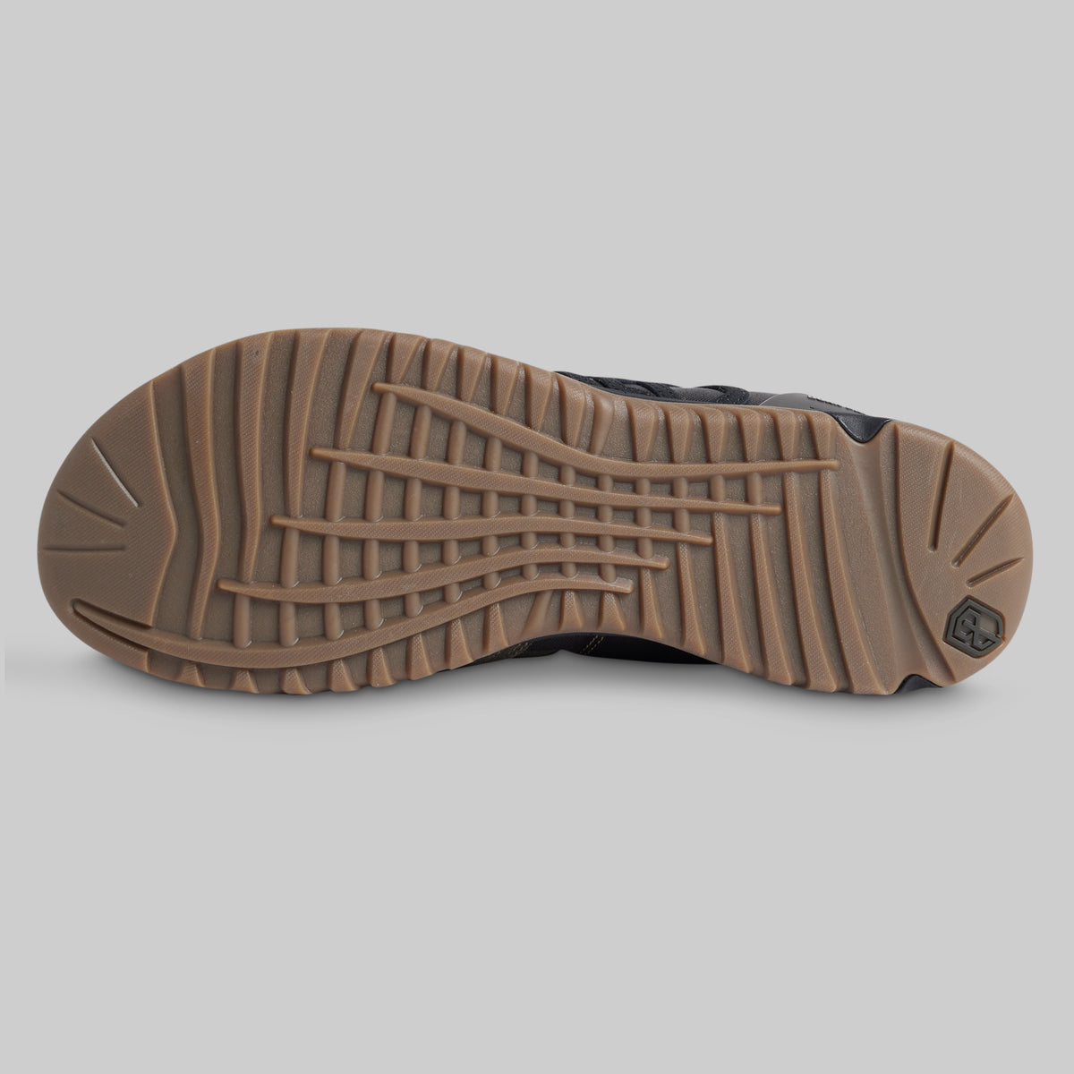 The outsole of a tactical boot or shoe, featuring a brown lug tread pattern and a small black logo on the heel, shown against a solid gray background.