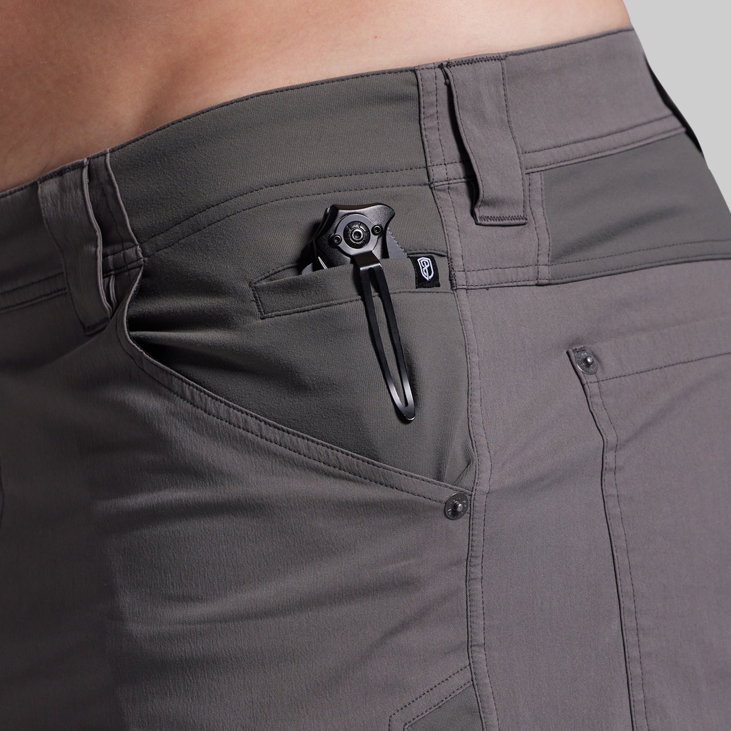 Close-up of gray shorts with a black clip on a neutral background