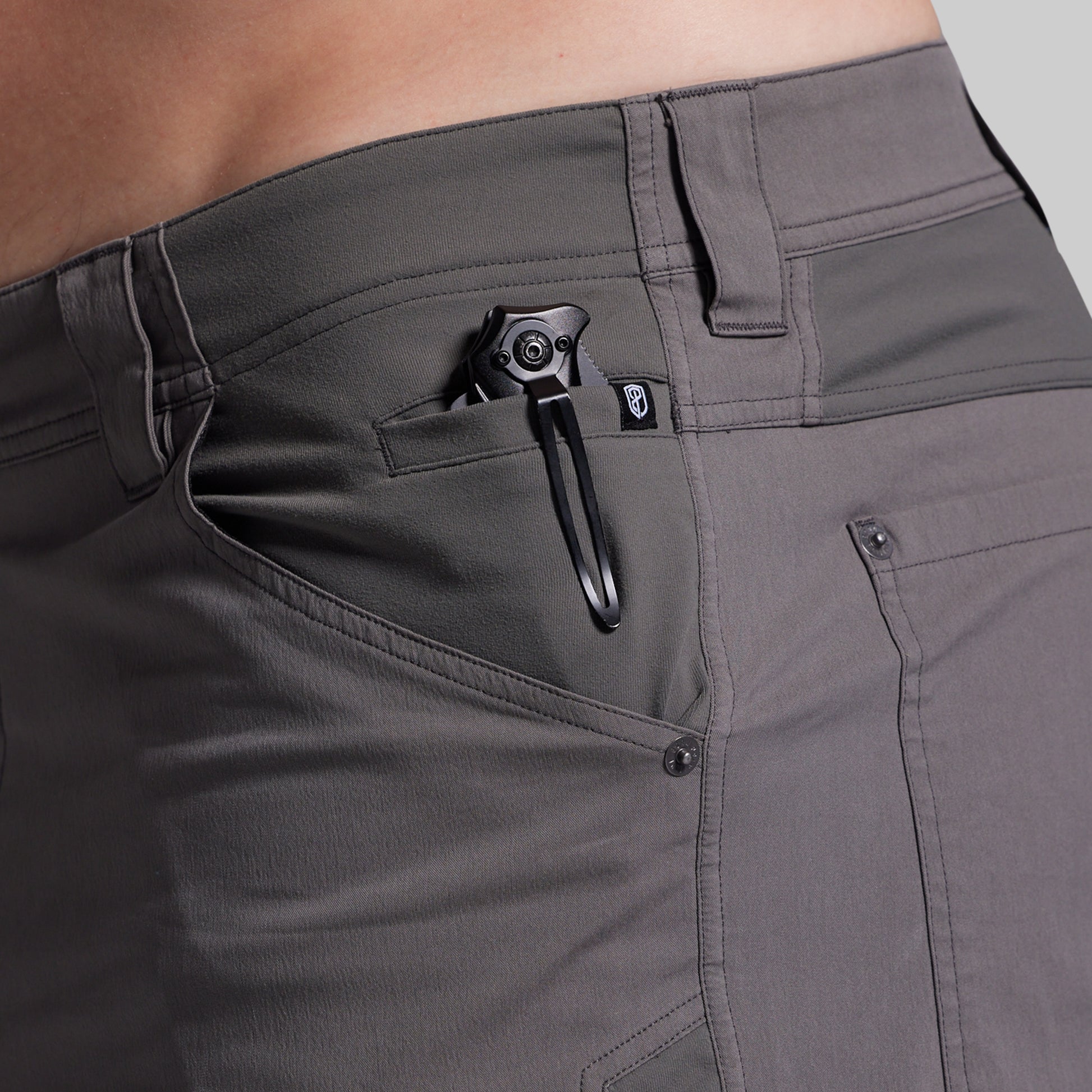 Close-up of gray shorts with a black clip on a neutral background