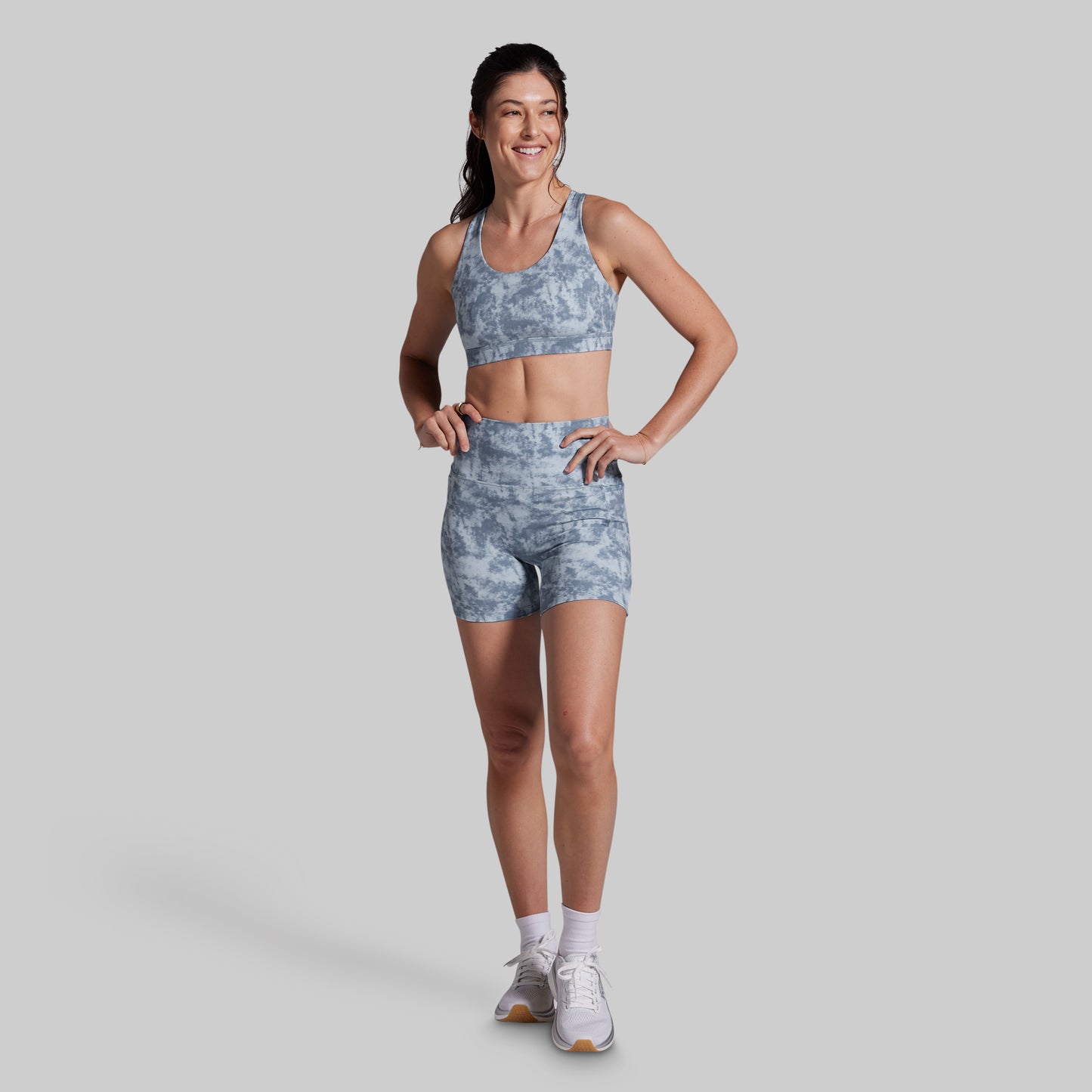 Woman wearing a gray athletic outfit on a light gray background