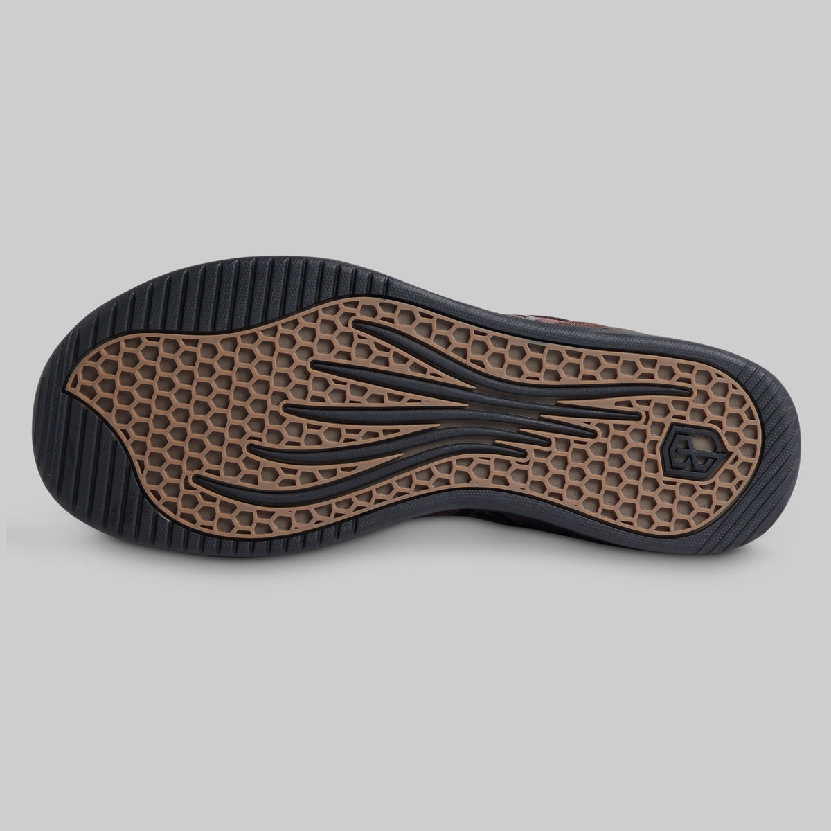 The outsole of a shoe shown from the bottom, featuring a black treaded edge and a brown honeycomb-patterned center with black wavy lines and a small logo.