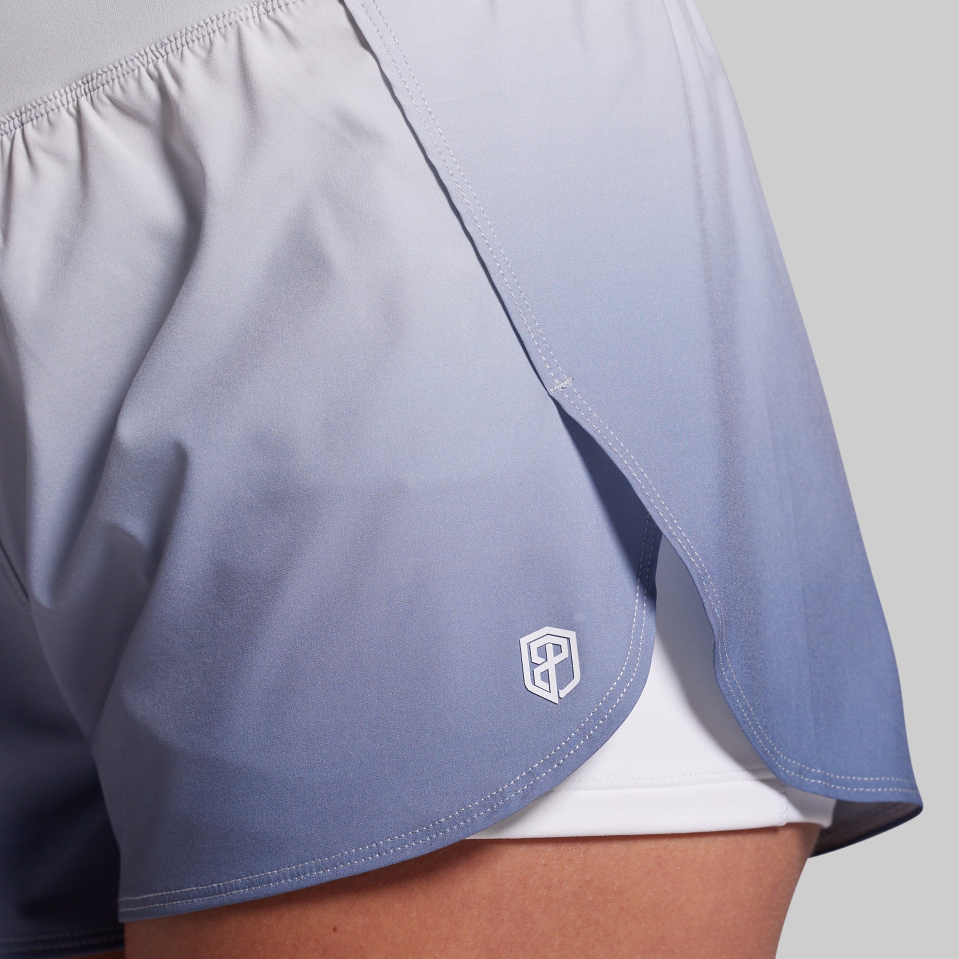 Light blue athletic shorts with a logo on a gray background