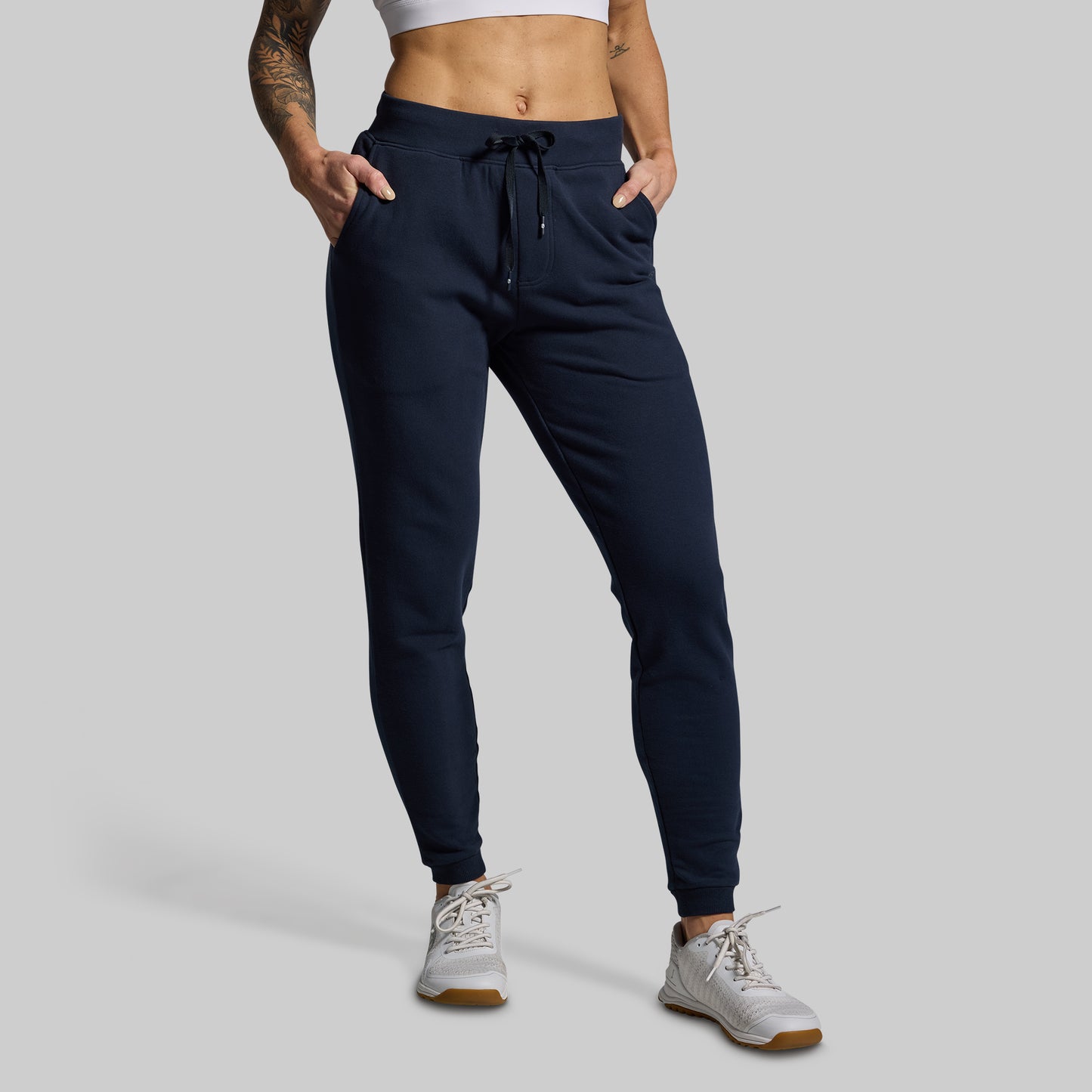 Person wearing navy jogger pants on a gray background