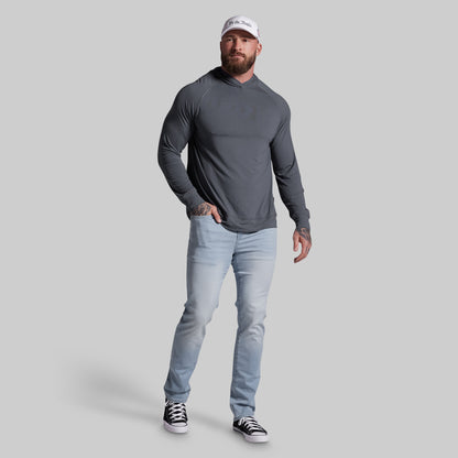 Man wearing a gray long-sleeve shirt, light blue jeans, and black sneakers on a gray background