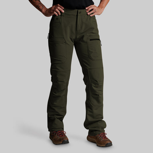 A person wearing dark olive green cargo pants with brown hiking boots, shown from the waist down against a light gray studio background.