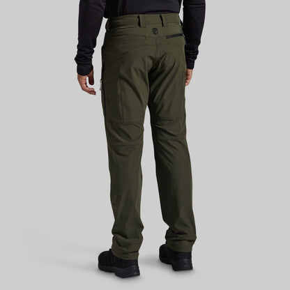 A person shown from the back wearing olive green technical cargo pants, a black long-sleeve top, and black shoes against a light gray studio background.