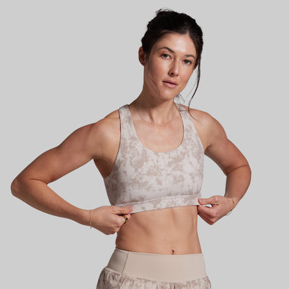 Woman wearing a patterned sports bra and shorts on a plain background