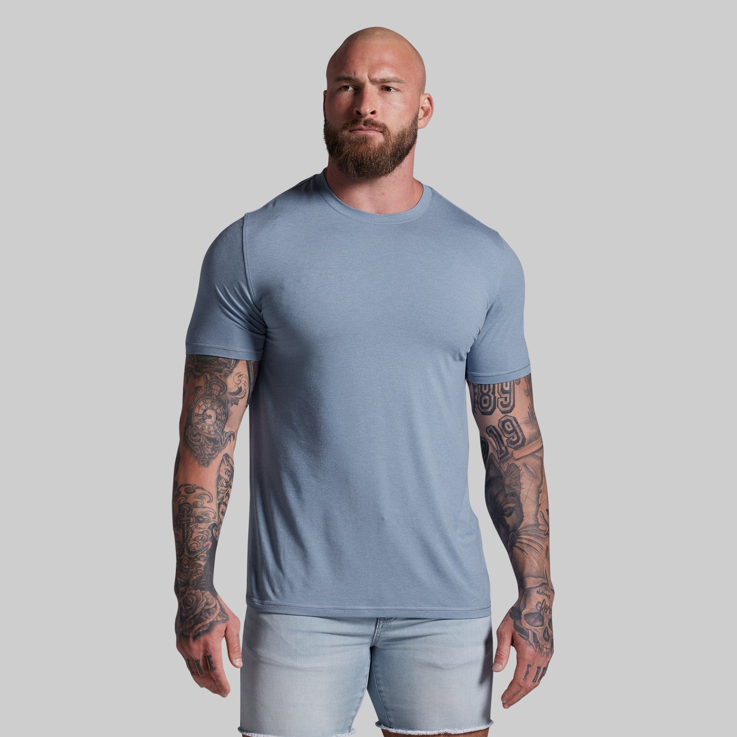 Man wearing a light blue t-shirt and shorts against a gray background