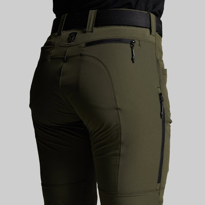 Close-up of a person wearing olive green outdoor pants with a black belt, showing the back pocket and zippered details.