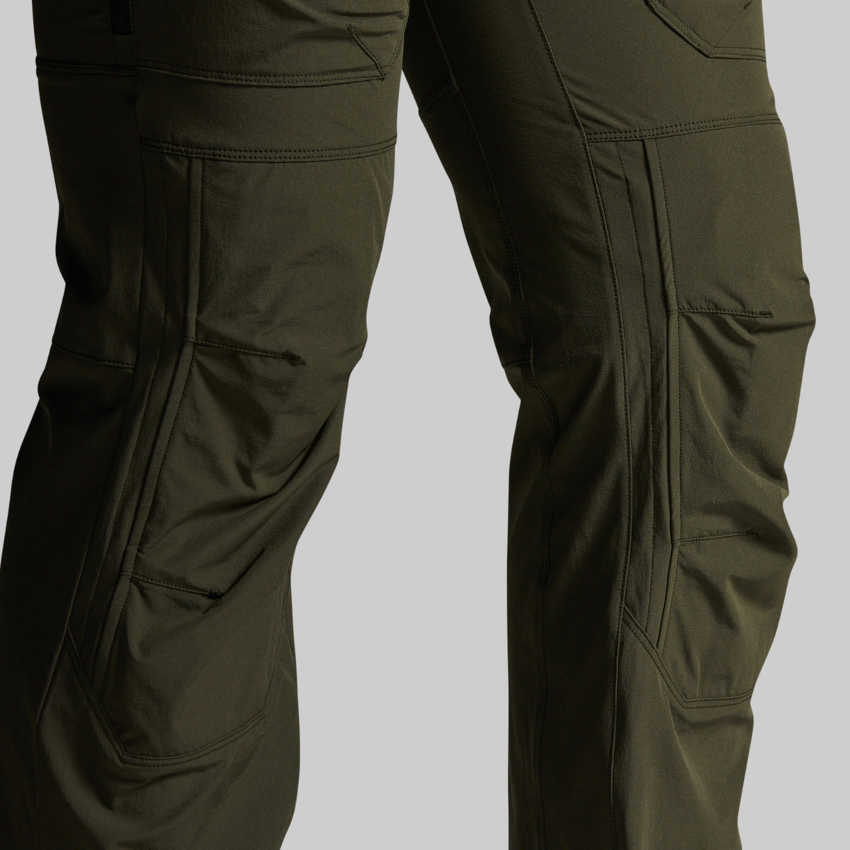Close-up of olive green cargo pants showing the thigh area with multiple utility pockets on a light gray background.