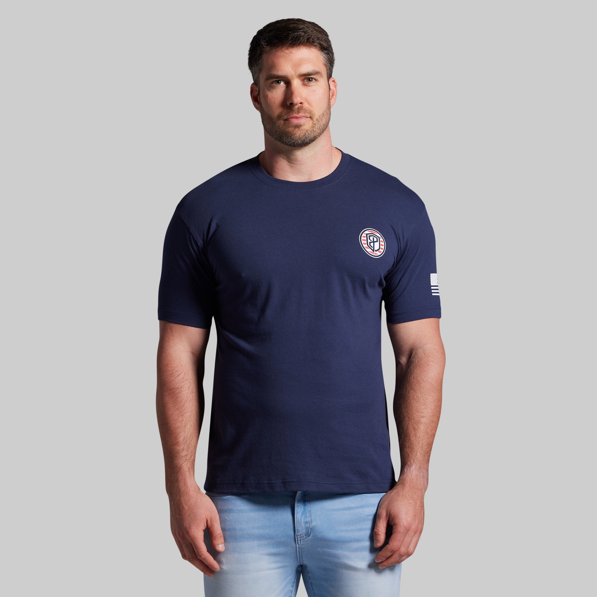 Man wearing a navy blue t-shirt with a logo on a gray background