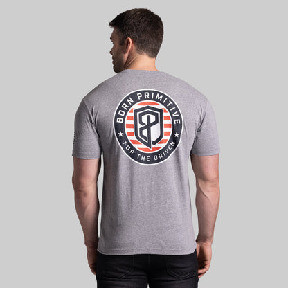 Man wearing a gray t-shirt with a 'Born Primitive' logo on the back against a light gray background