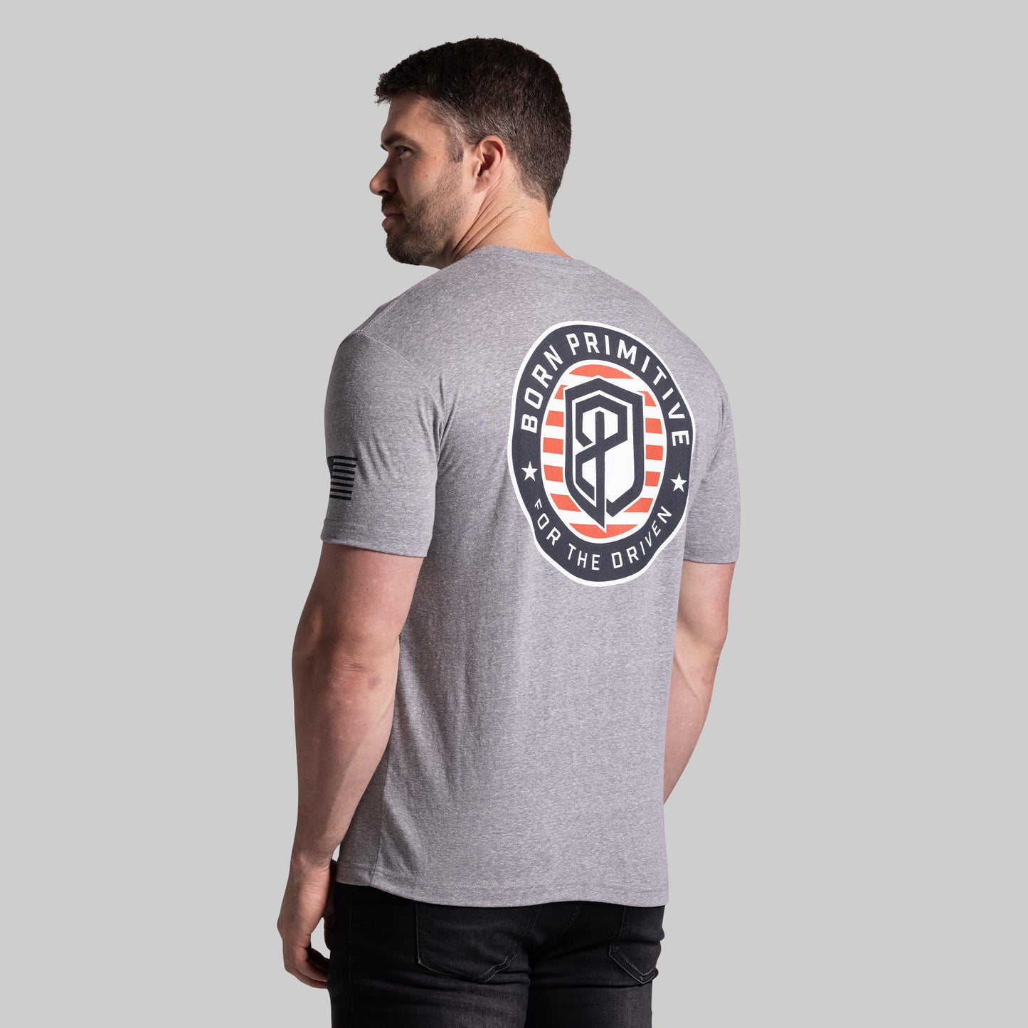 Man wearing a gray t-shirt with a logo on the back against a plain background
