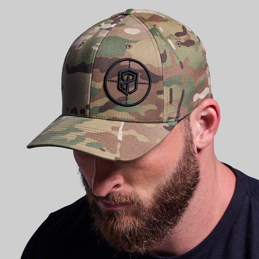 Man wearing a camouflage cap with a logo on a gray background