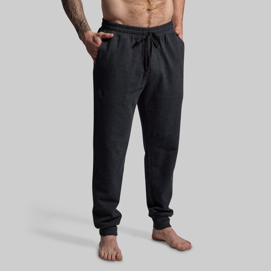 Person wearing dark gray jogger pants on a light gray background