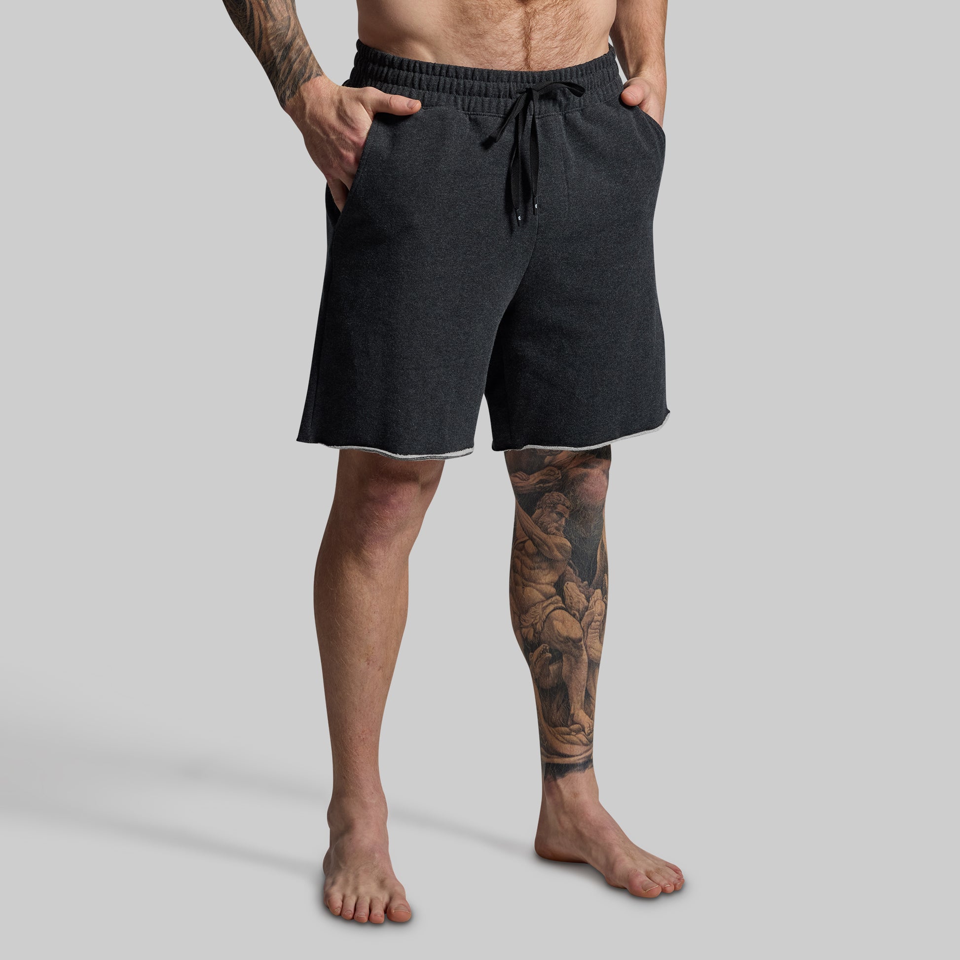 Person wearing dark grey shorts on a gray background