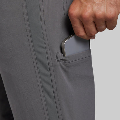 Close-up of a person's hand pulling a smartphone out of a side pocket of gray pants.