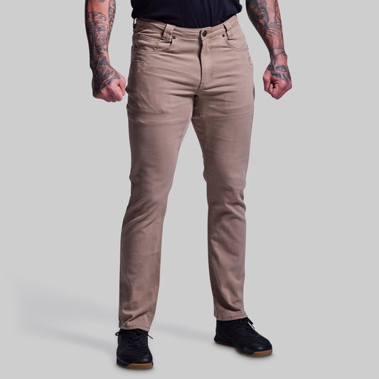 Person wearing beige jeans on a plain background