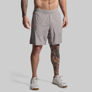 Man wearing light gray shorts on a plain background