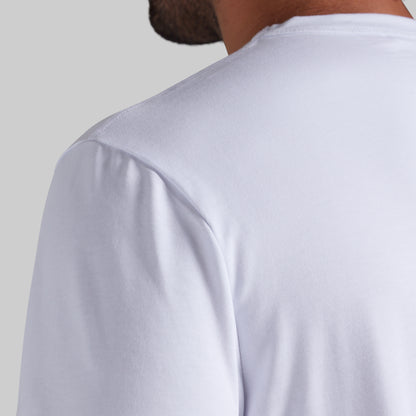 Close-up back view of a person wearing a plain white short-sleeve t-shirt against a light gray background.