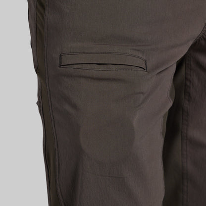 Close-up of dark brown pants showing a side pocket and fabric texture against a light gray background.