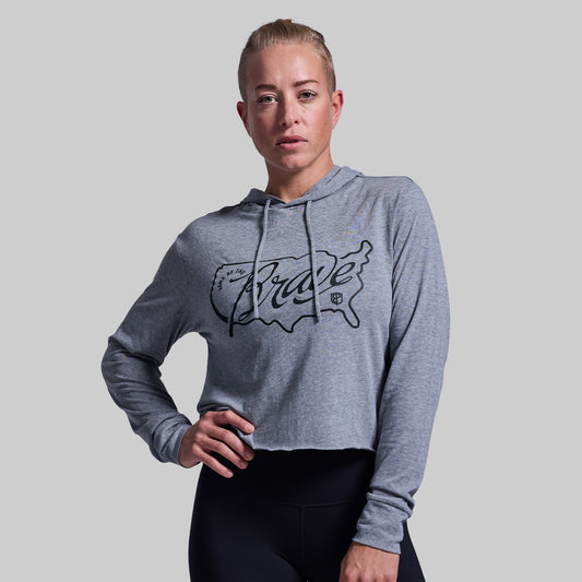 Woman wearing a gray hoodie with a logo on a plain background