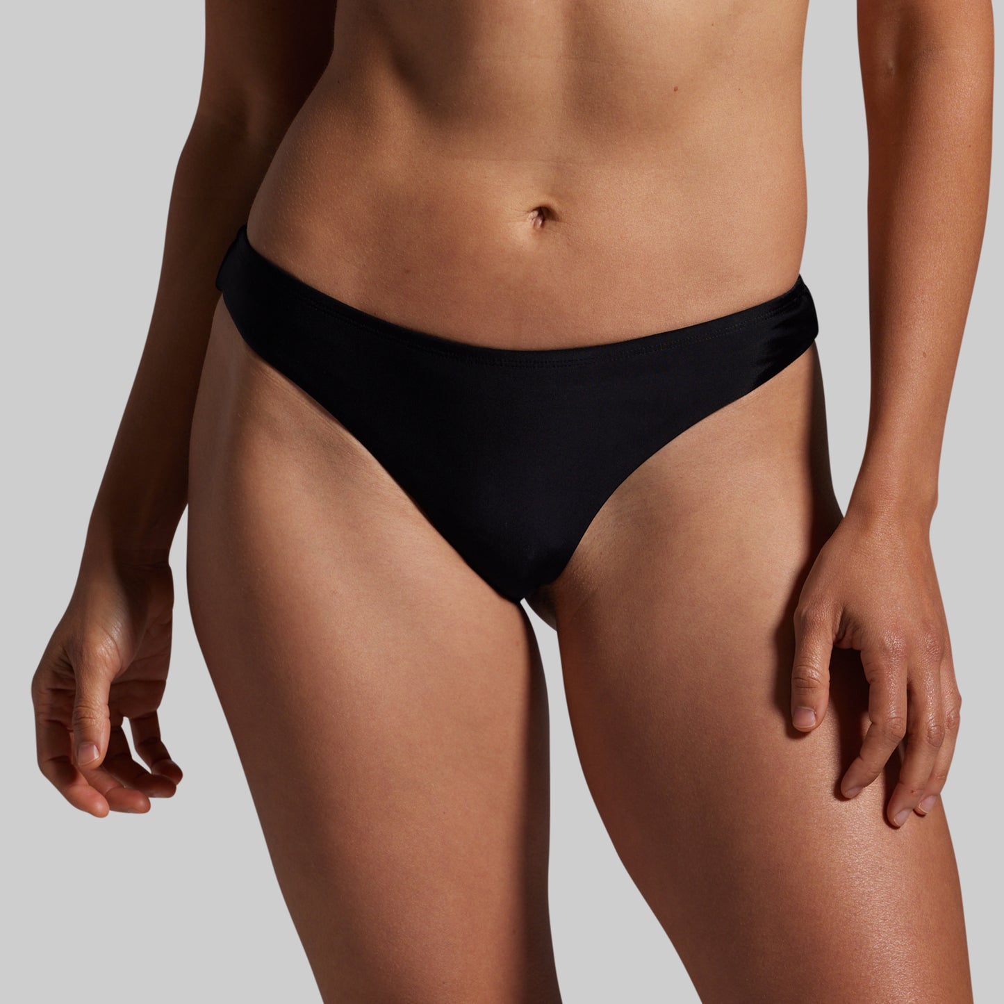 Person wearing a black bikini bottom on a plain background