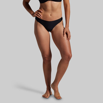 Person wearing black bikini bottoms on a gray background