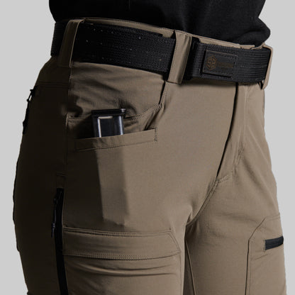 Close-up of storm grey outdoor cargo pants worn with a black web belt and black shirt, showing side pockets and a magazine in the side pocket.