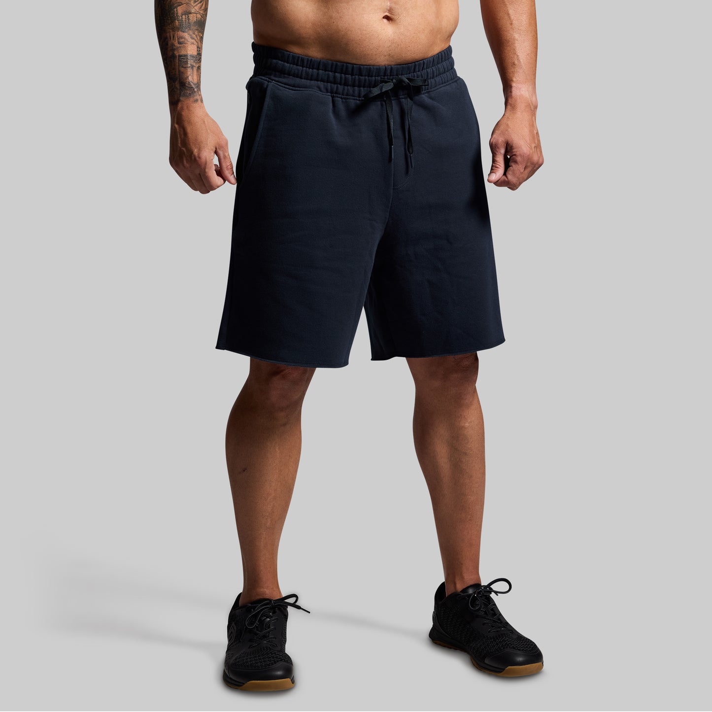 Person wearing navy shorts on a gray background