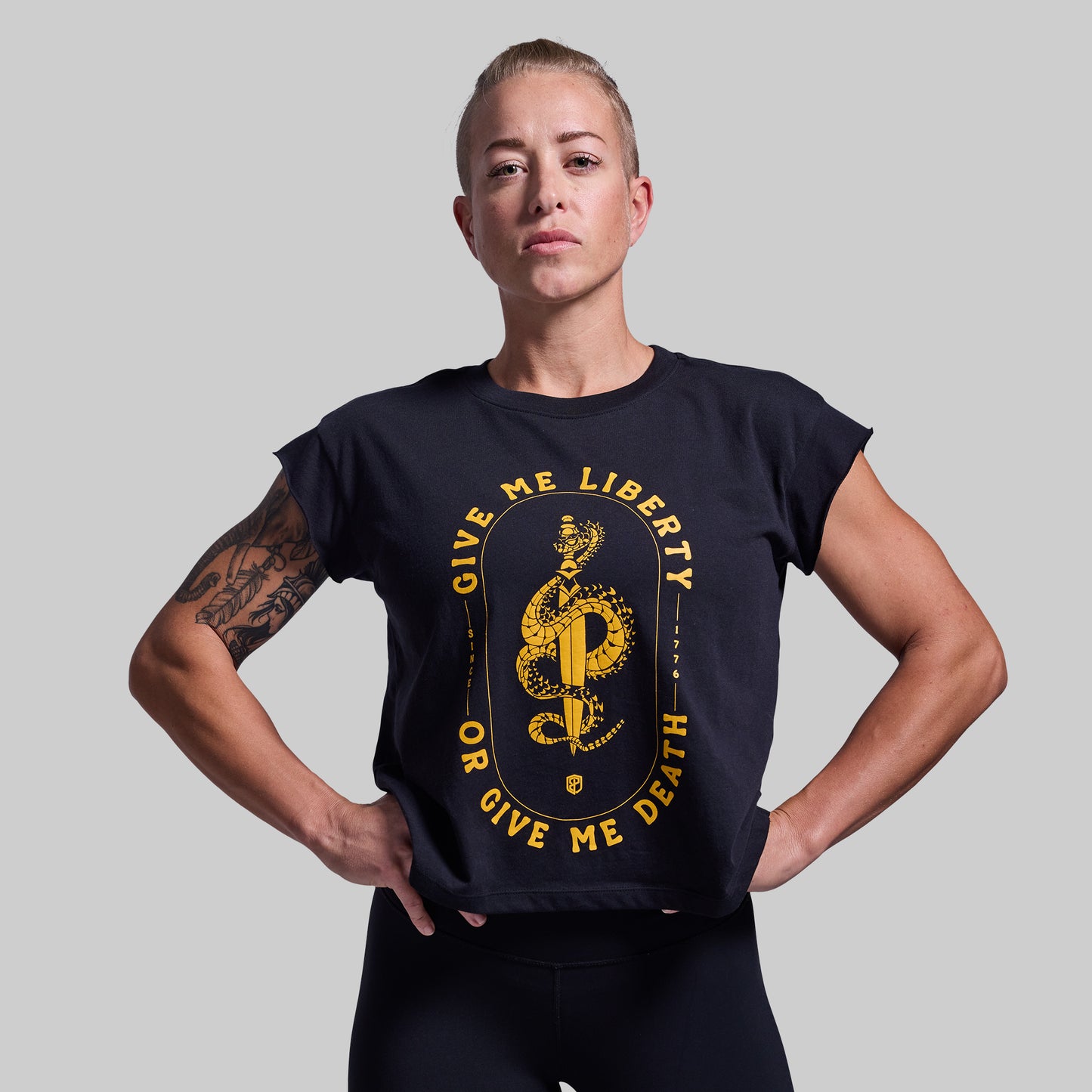 Person wearing a black t-shirt with yellow text and design on a plain background