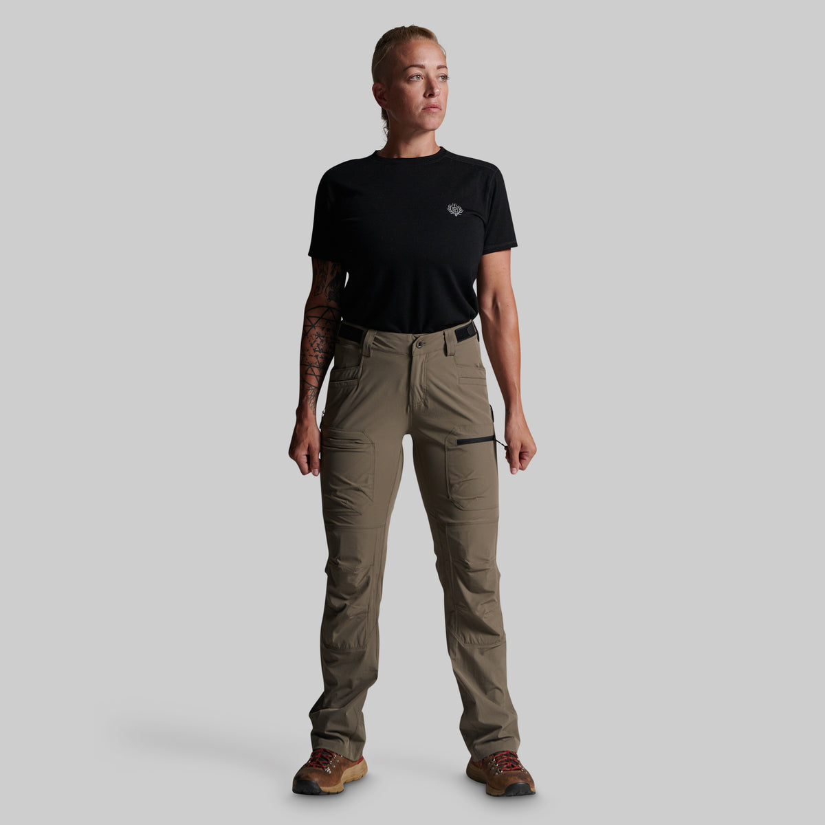 A model wearing a black short-sleeve t-shirt and storm grey cargo pants, standing against a solid gray background.