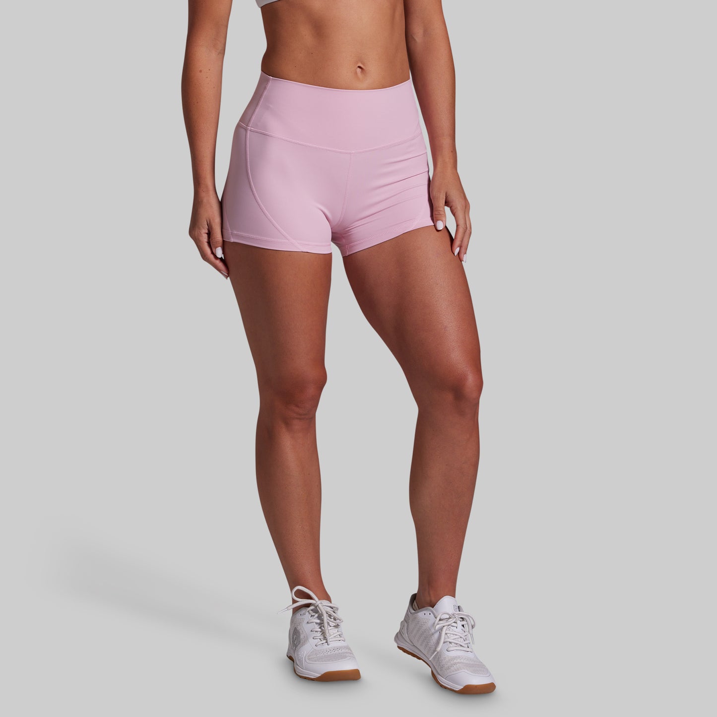 Person wearing pink athletic shorts on a gray background