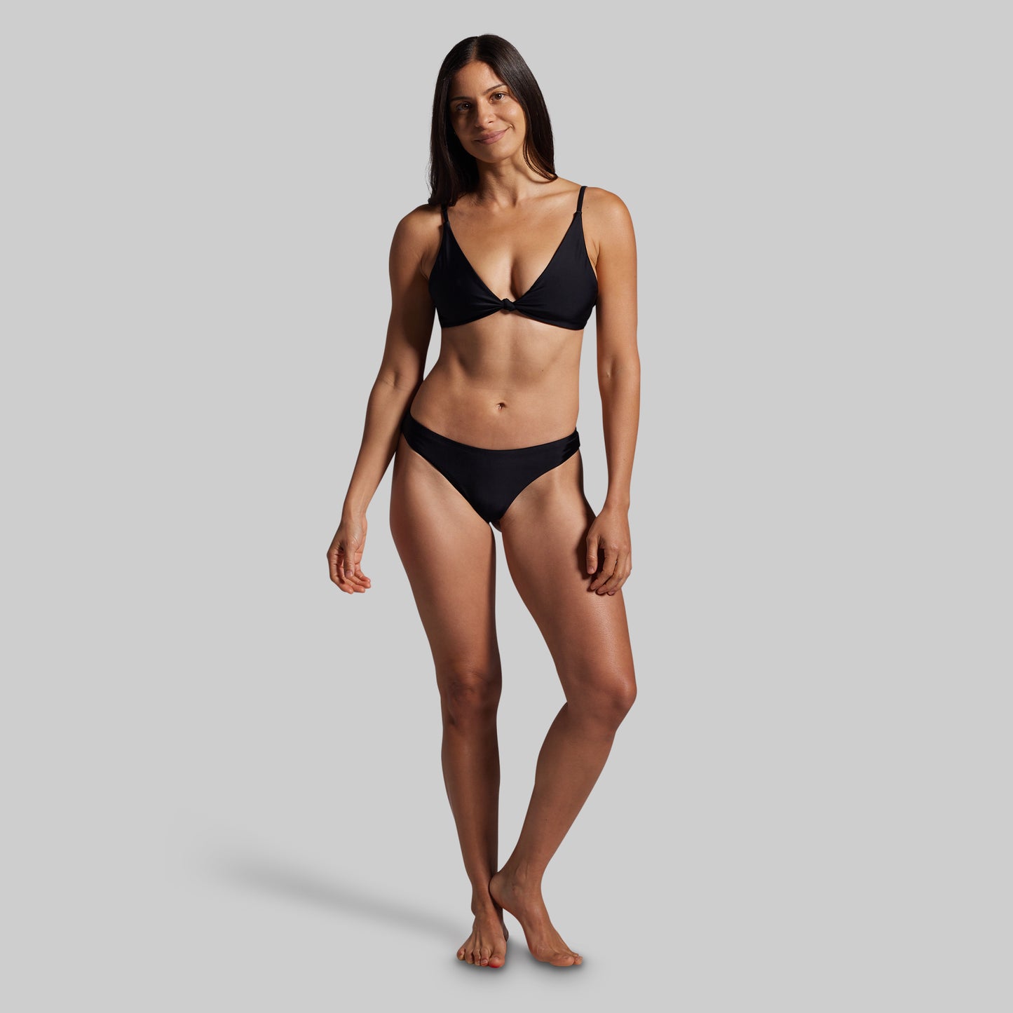 Woman wearing a black bikini against a gray background