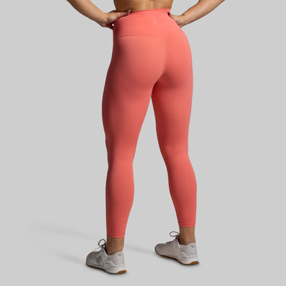 Person wearing coral leggings on a gray background