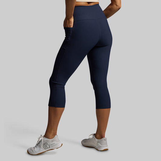 Woman wearing blue capri leggings on a gray background
