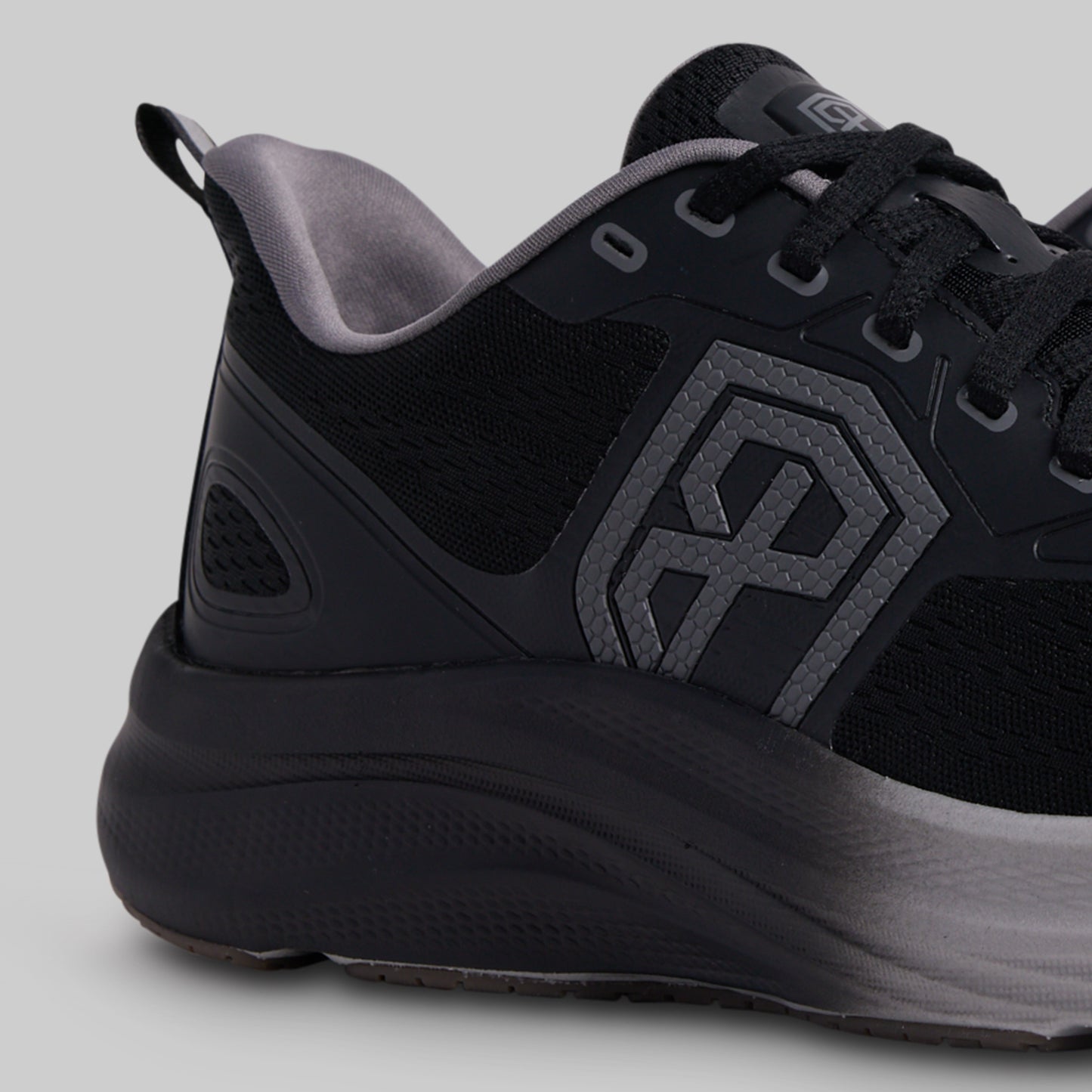 Black athletic shoe with a geometric logo on a gray background