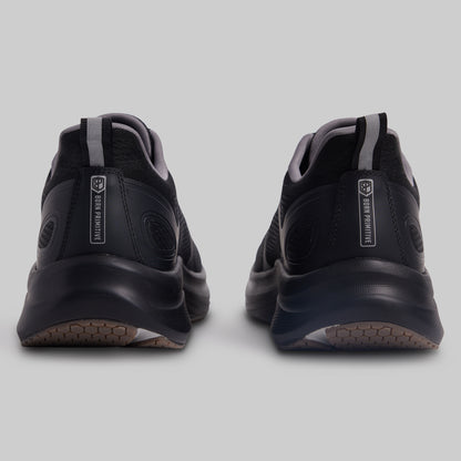 Black athletic shoes with visible branding on a light gray background