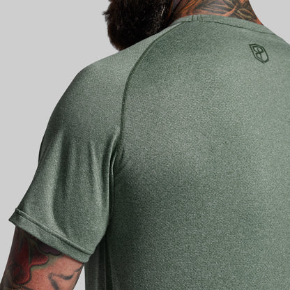 Green athletic shirt with a logo on the back, worn by a person with tattoos.