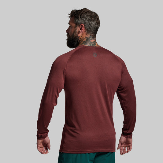 Man wearing a maroon long-sleeve shirt on a gray background
