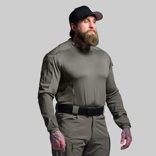 Man wearing a green tactical outfit with a black cap on a gray background