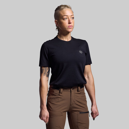 Person wearing a black t-shirt and brown pants on a gray background
