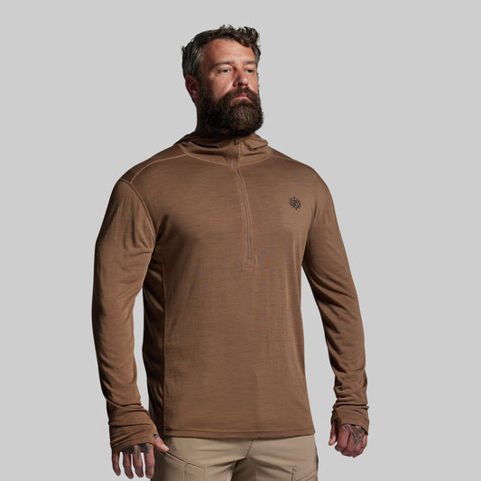Man wearing a brown long-sleeve shirt with a logo on a gray background